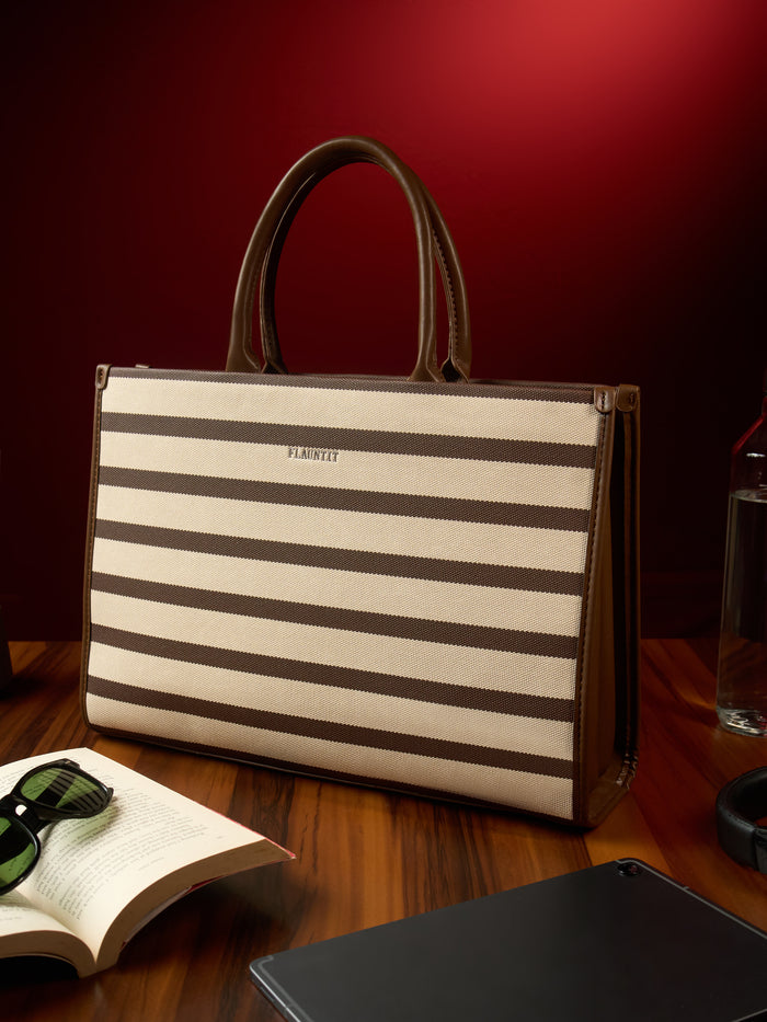 The brown striped Soft tote on a desk beside a book